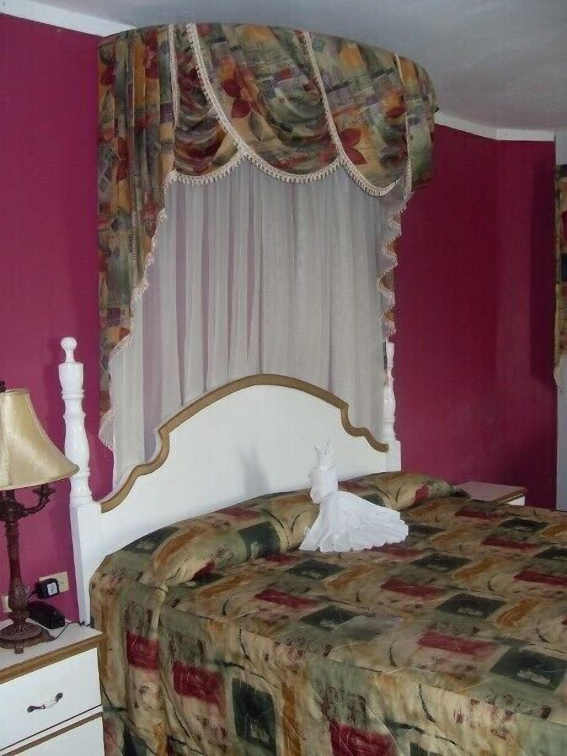 A room with a bed, a nightstand, a lamp, and a decorative canopy.