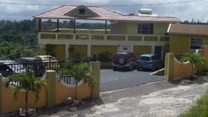 A two-story building with a red-tiled roof, a gated entrance, and parked cars. - Mandeview Hotel (Mandeville)