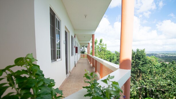A long corridor with a balcony, leading to a view of a lush green landscape. - Mandeview Hotel (Mandeville)