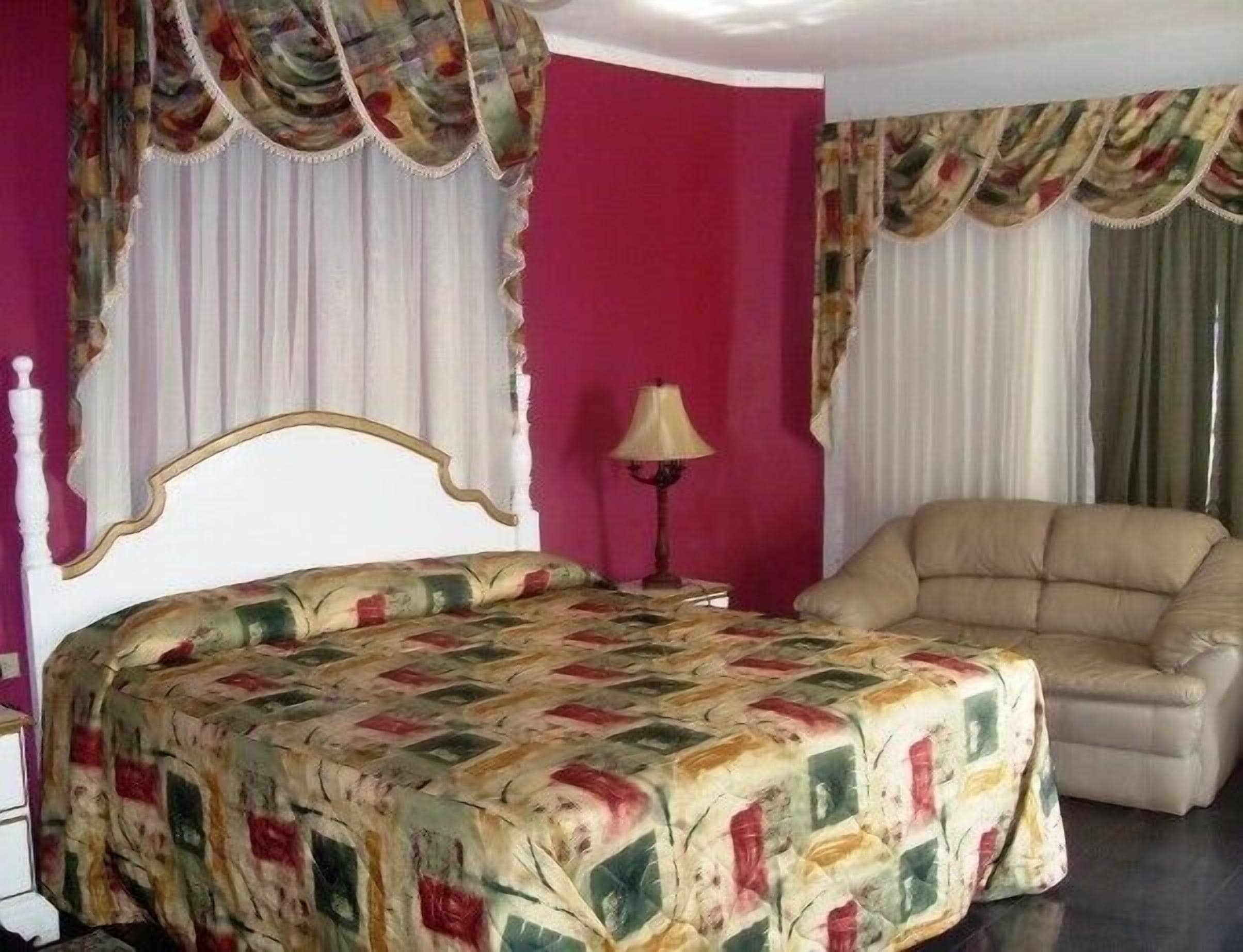 Un dormitorio con cama, una silla y cortinas.