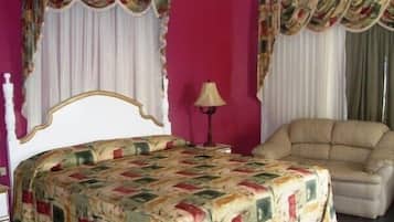 Un dormitorio con cama, una silla y cortinas.