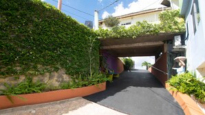 A narrow alleyway with a concrete bridge overhead, surrounded by lush greenery and a building on one side. - Mandeview Hotel (Mandeville)