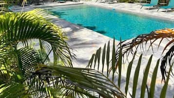A swimming pool surrounded by palm trees and lounge chairs.