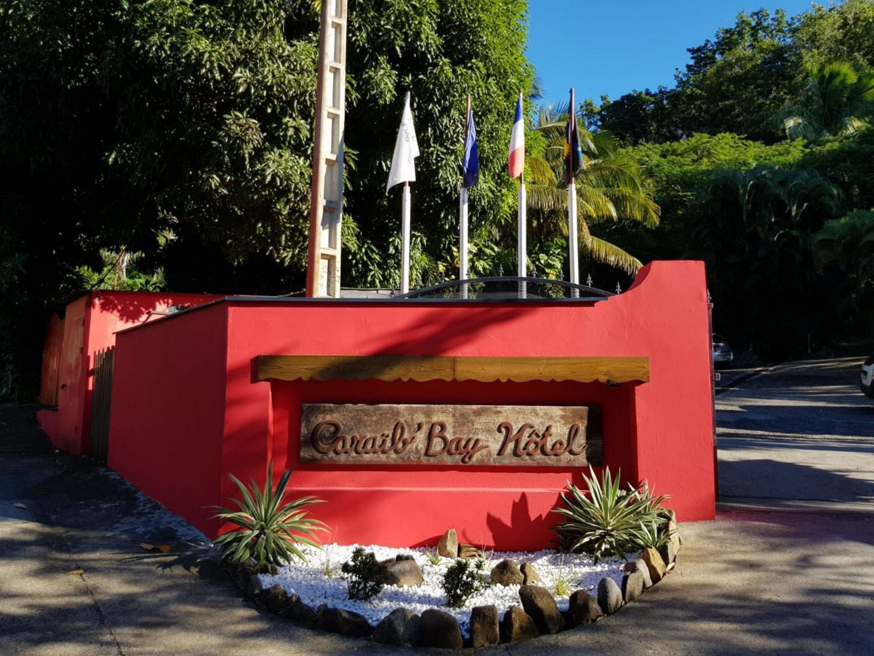 A red building with a sign that reads "Cairn Bay Hotel". There are flags on top of the building.