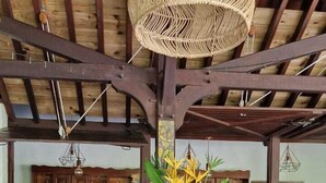 Una zona de bar con vigas de madera, una lámpara de fibra y un taburete.