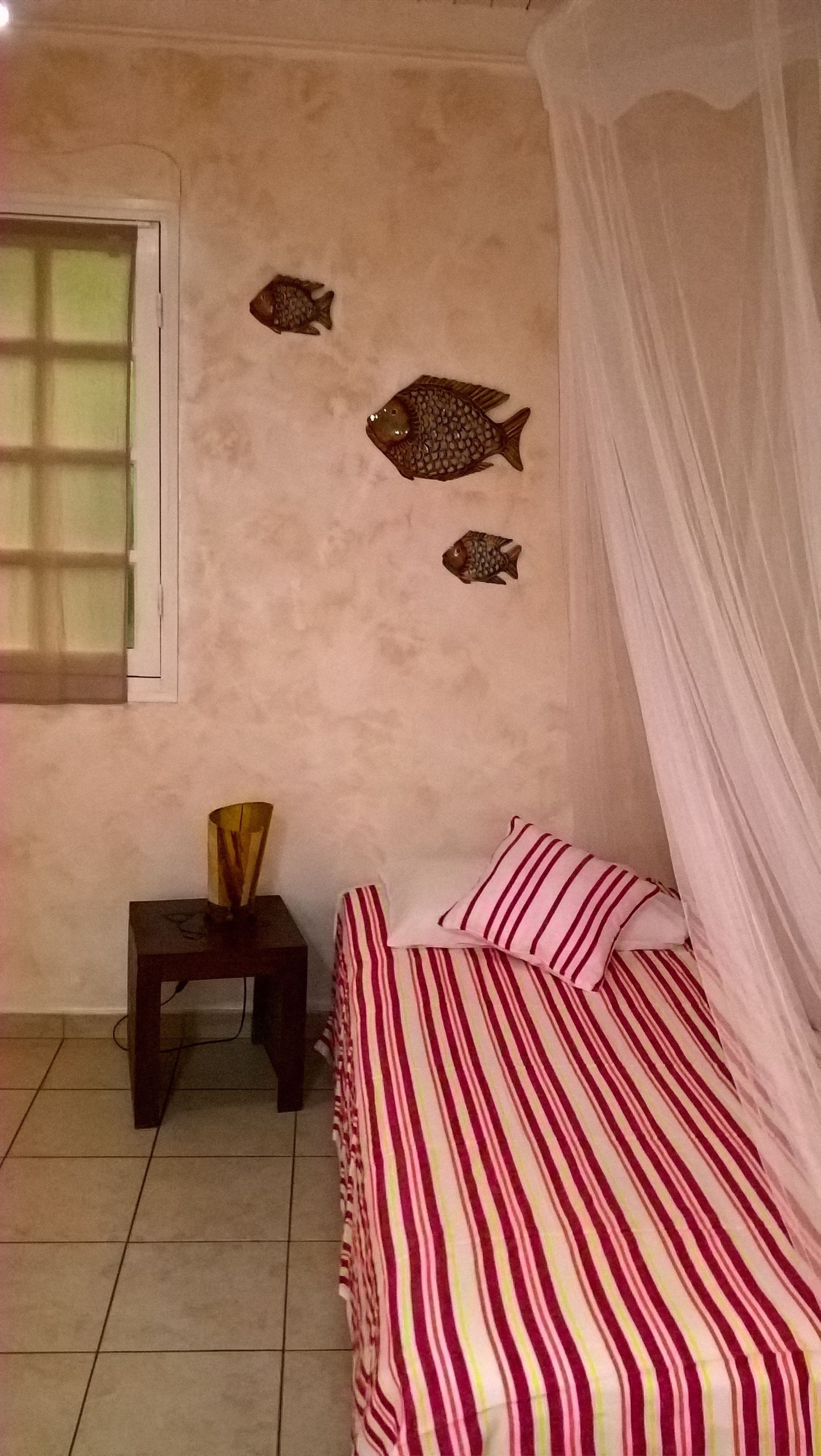 A bedroom with a bed, a bedside table, a lamp, and wall decorations.