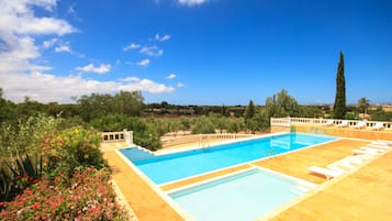 Relax by the pool surrounded by lush greenery and lounge chairs.