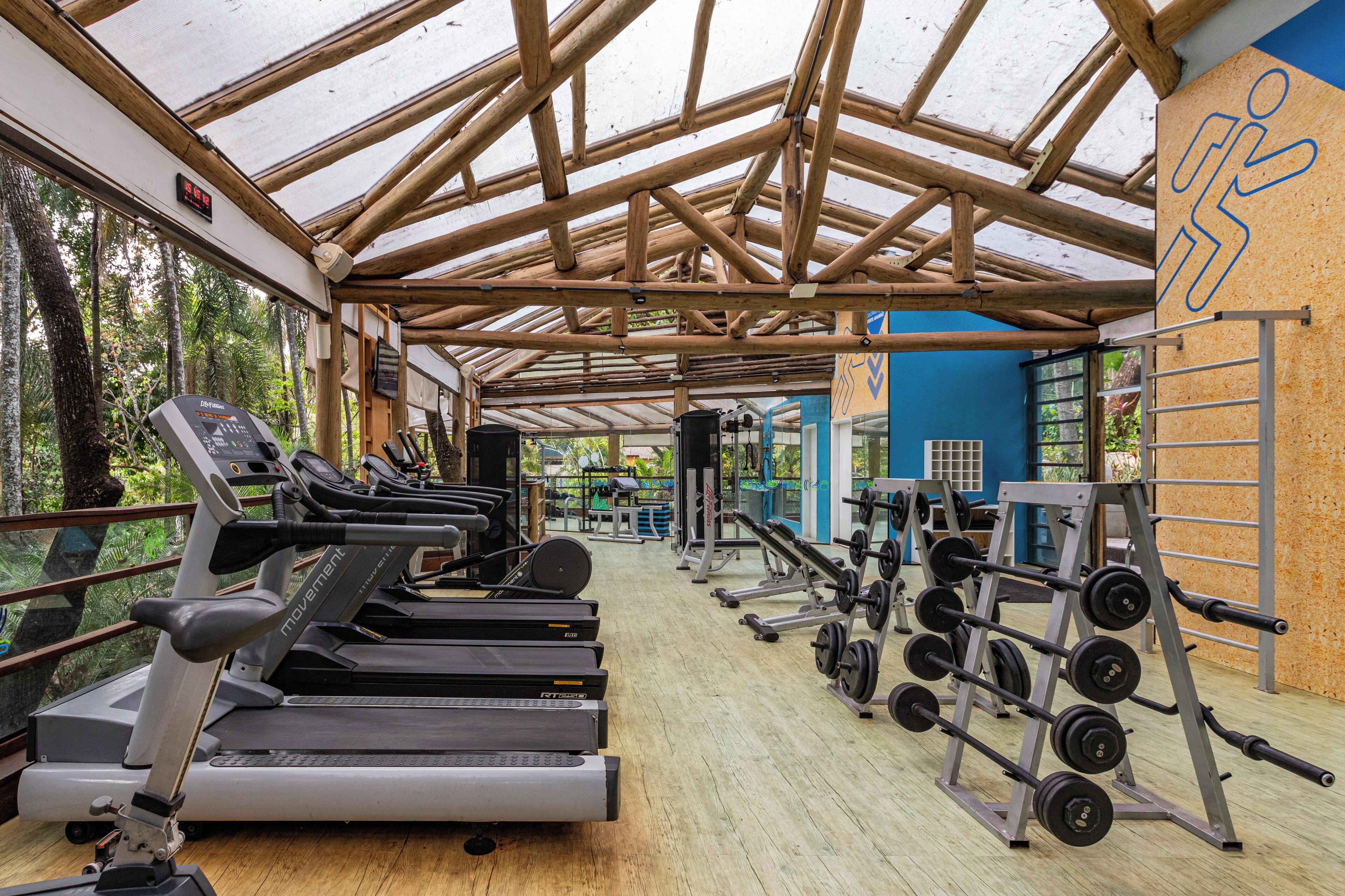 Et fitnesscenter med løbebånd, træningsmaskiner og et træloft.