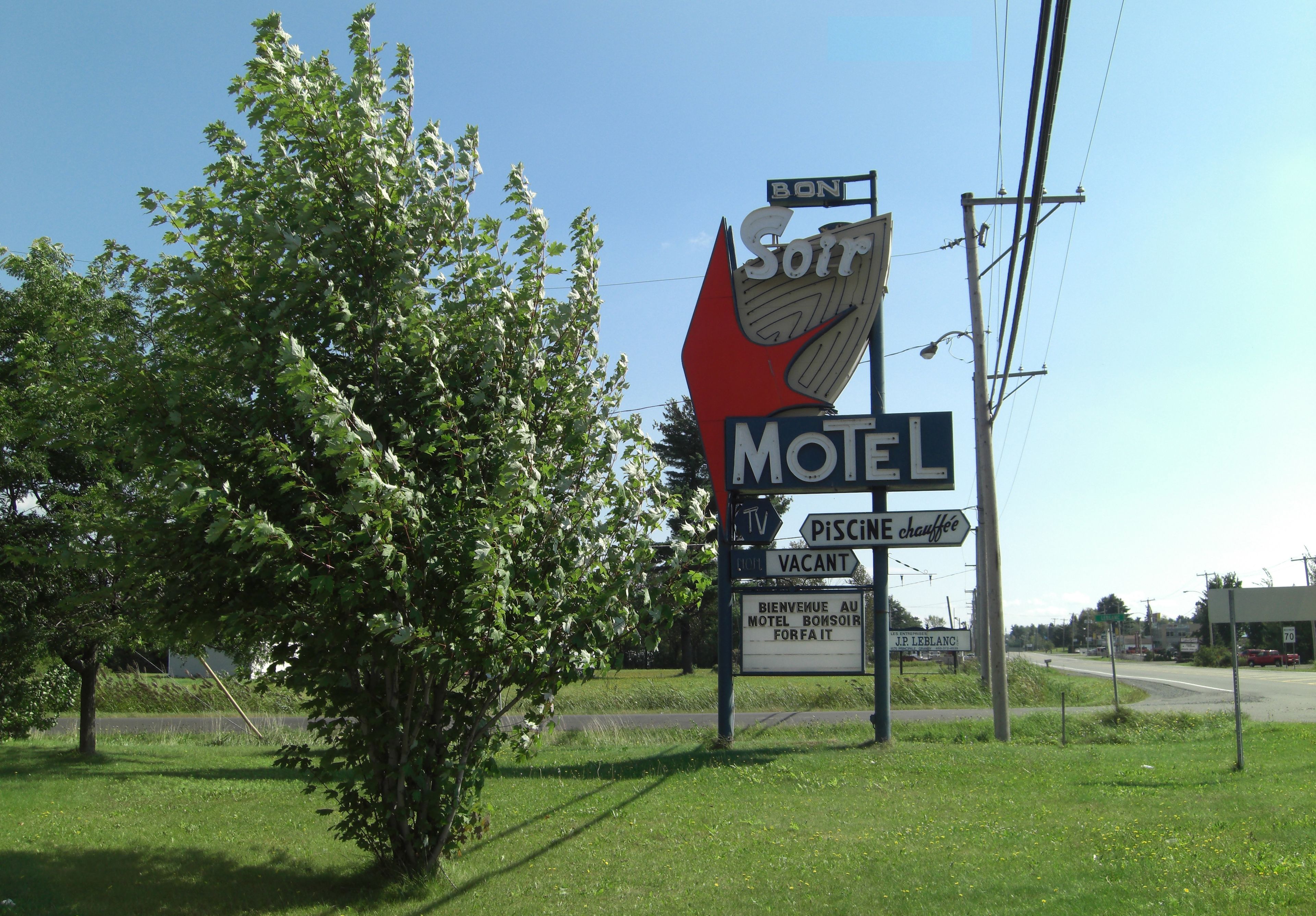 Letrero de motel con una bandera roja e indicación de que hay habitaciones disponibles.