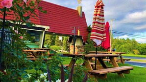 Un jardín con mesas de picnic y un edificio de techo rojo.