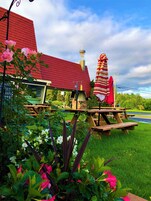 Un jardín con mesas de picnic y un edificio de techo rojo.