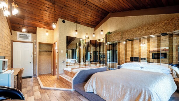 Un dormitorio con una cama grande, techo de madera y un baño con ducha y espejo.