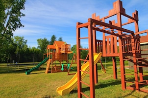 Un parque infantil con un tobogán amarillo y una estructura para escalar.