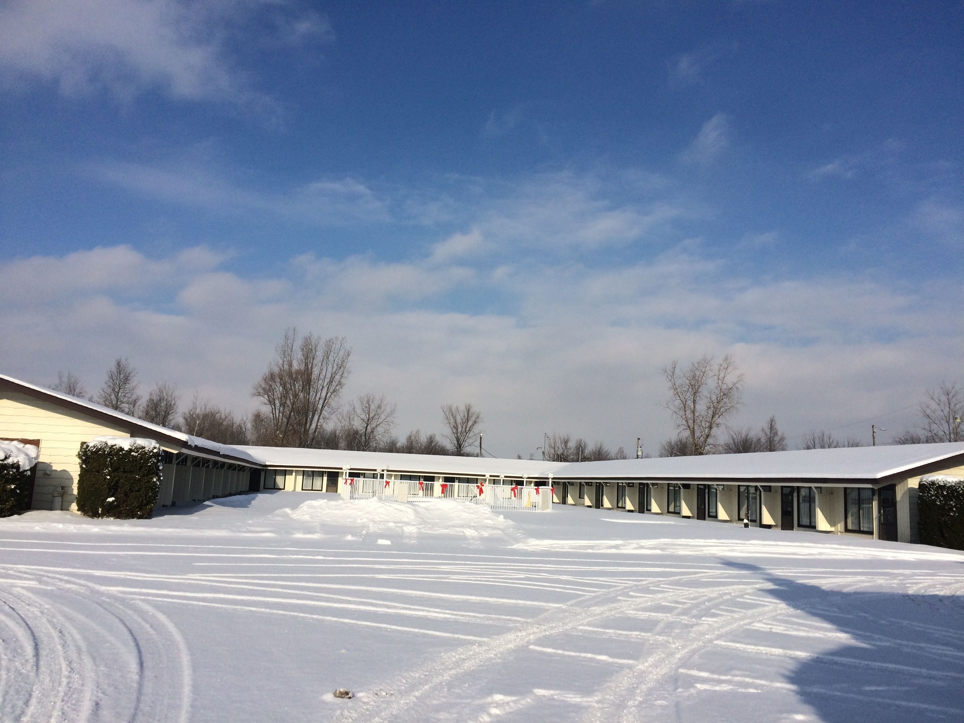 A snow-covered parking lot with a row of buildings.