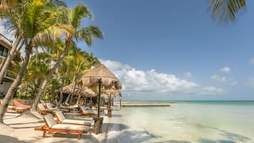 Een privéstrand, wit zand, ligstoelen aan het strand, strandlakens