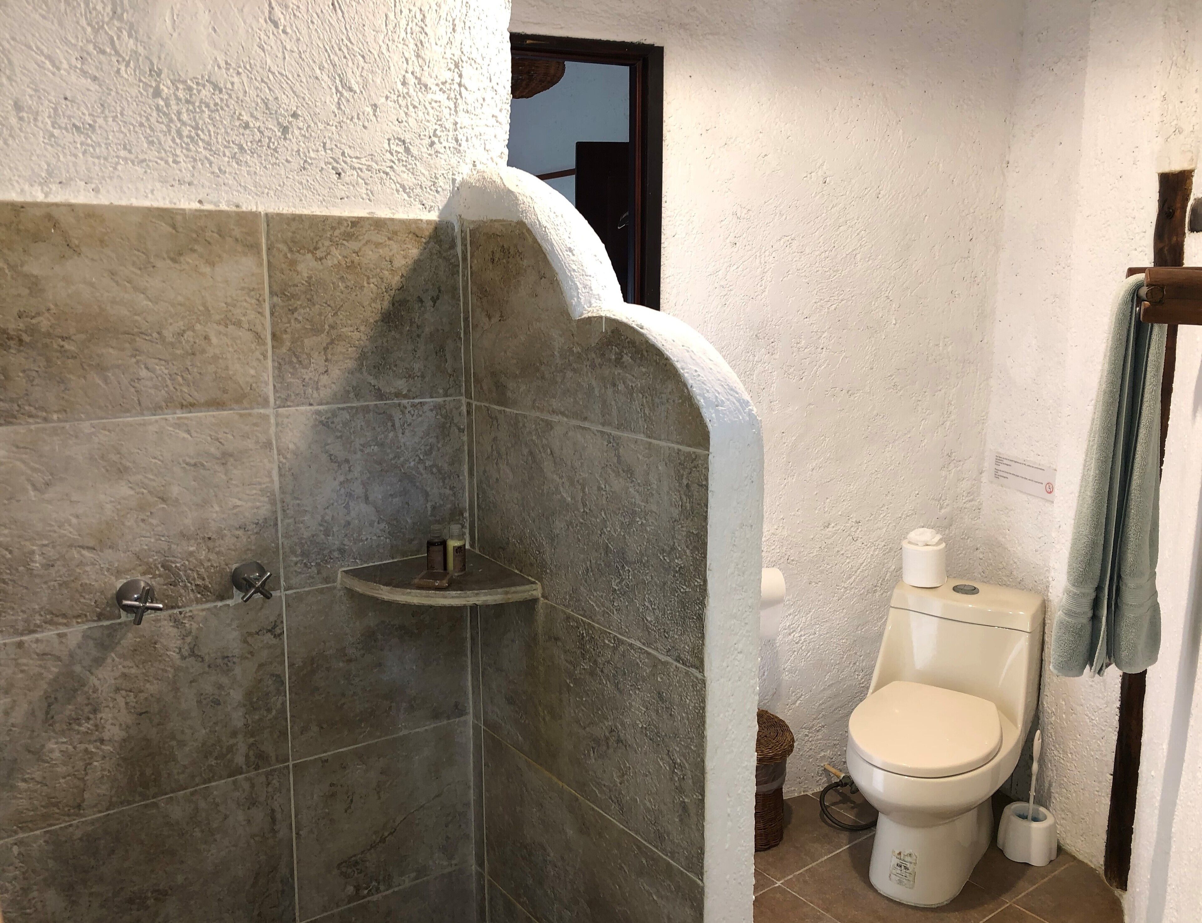 Un baño con ducha, inodoro y toallero.