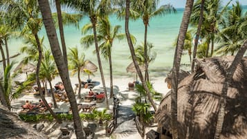 Een privéstrand, wit zand, ligstoelen aan het strand, strandlakens