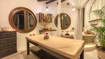 Relax in a serene space with a central massage table, flanked by mirrors and a wooden cabinet.