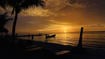 Een privéstrand, wit zand, ligstoelen aan het strand, strandlakens