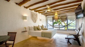 A room with a wooden ceiling, a white sofa with cushions, a wooden dining table, and a hammock. - Beachfront Hotel La Palapa - Adults Only (Isla Holbox)