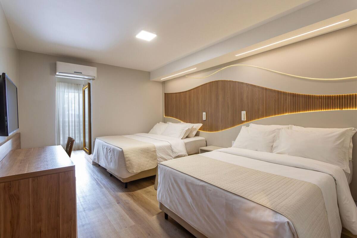 Une chambre d’hôtel avec deux lits, un bureau et une télévision.