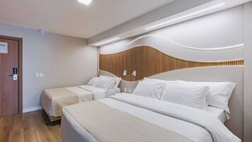 A modern hotel room with two beds, a wooden headboard, and a wall-mounted light fixture.