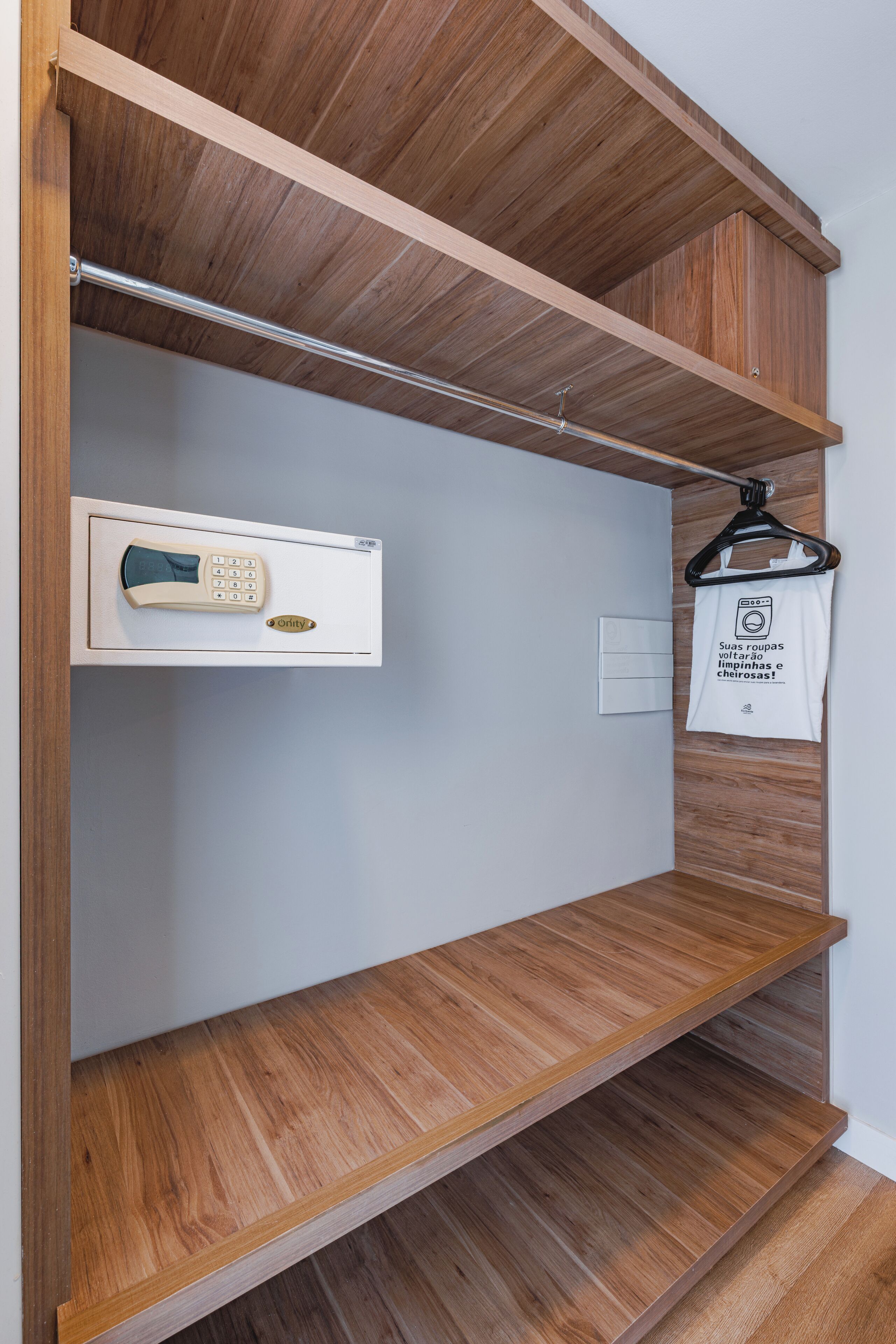 Un placard en bois, doté d’étagères, d’une tringle pour suspendre les vêtements et d’une porte avec un panneau de commande.