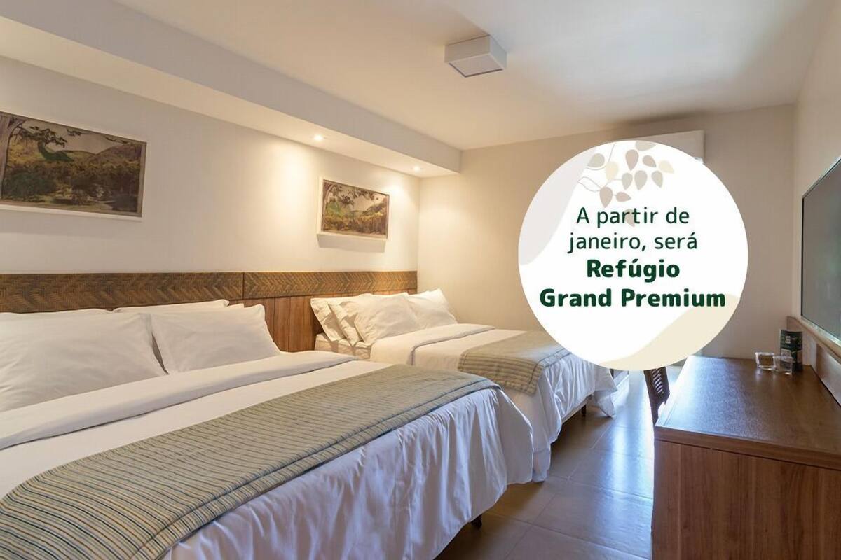 Une chambre d’hôtel avec deux lits, une tête de lit en bois et des œuvres d’art accrochées aux murs.