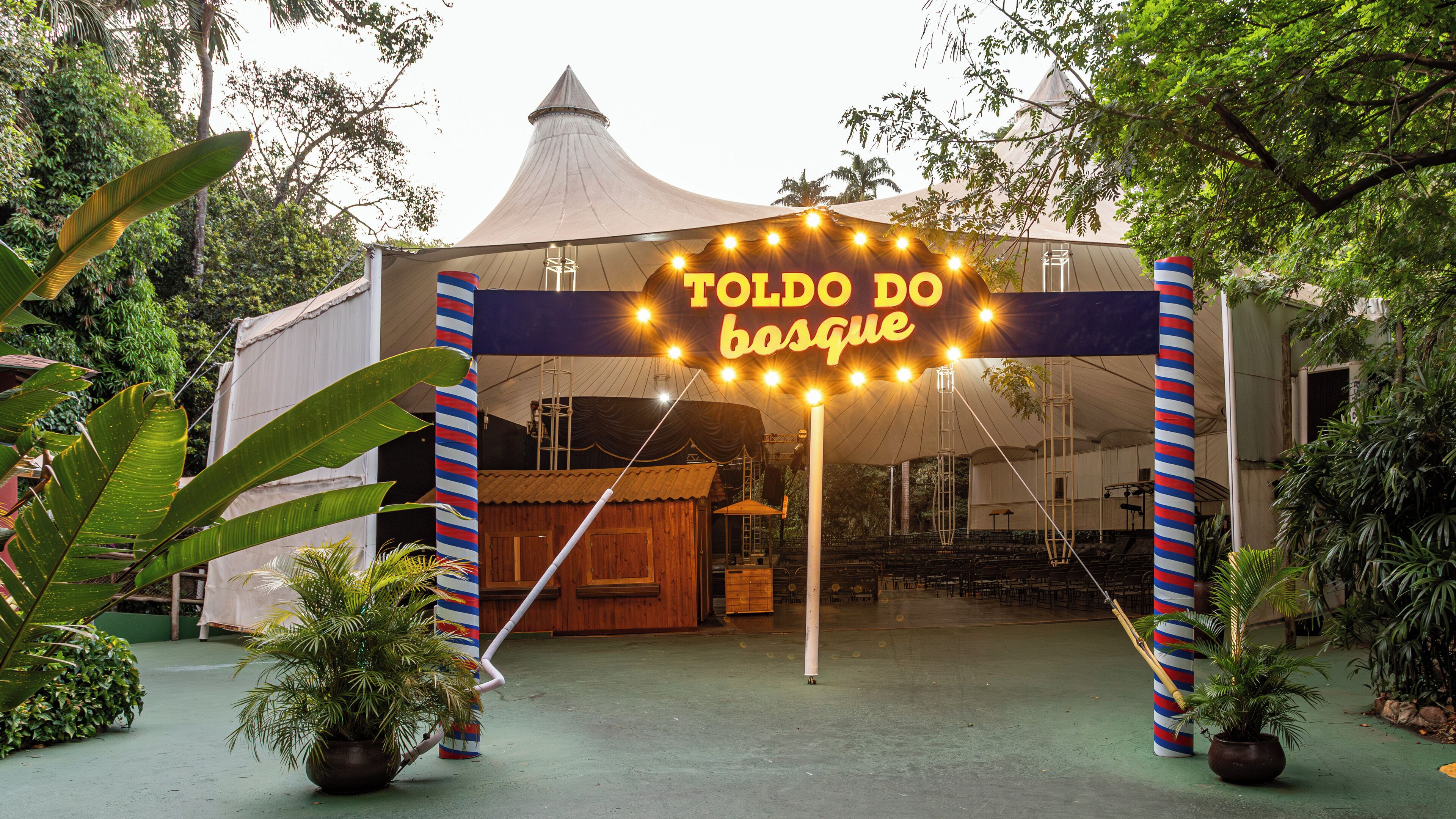 Un espacio al aire libre techado con un letrero que dice "TOLDO DO bosque" y una estructura de madera en su interior.
