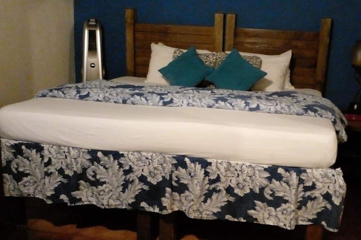 A bed with a floral bedspread, a wooden headboard, and two teal pillows.
