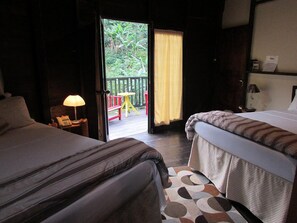 A hotel room with two beds, a small table with a lamp, a view of the outdoors through a glass door, and a wooden deck with a red chair. - RafJam Bed & Breakfast (Newcastle)