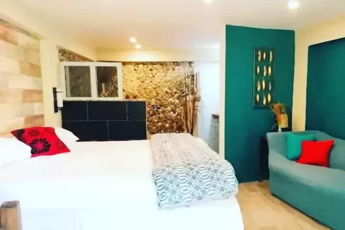 A bedroom with a bed, a sofa, and a stone wall.