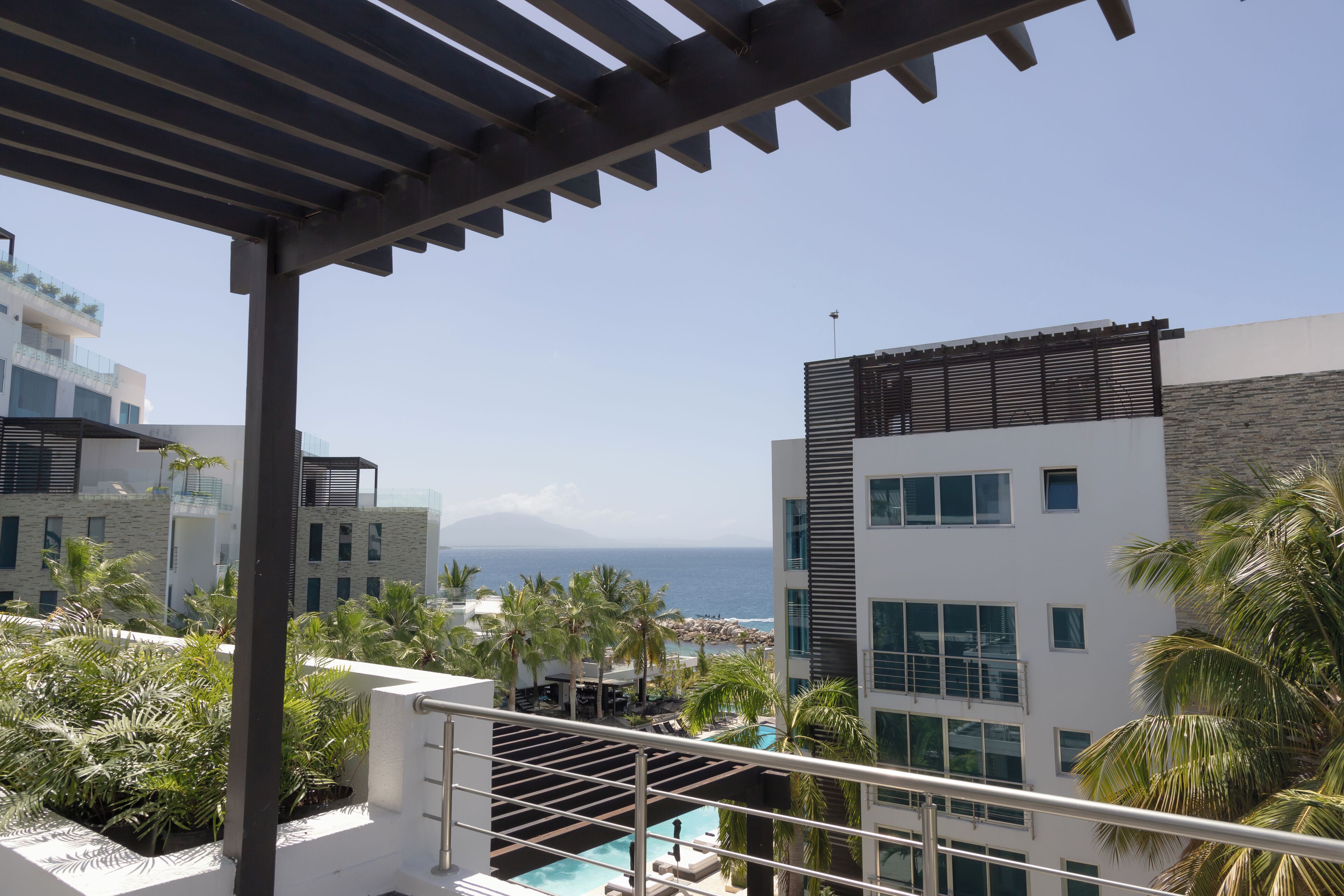 Un hotel moderno con zona de piscina, palmeras y vista al océano.