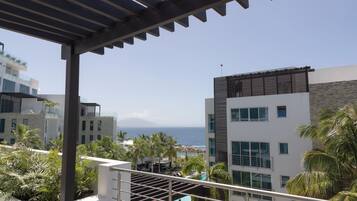 Un hotel moderno con zona de piscina, palmeras y vista al océano.