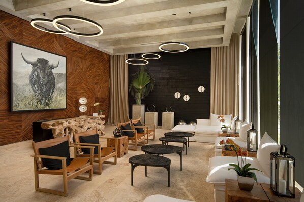 Un salon moderne avec des meubles en bois, un tableau représentant un taureau et un mur en briques noires.