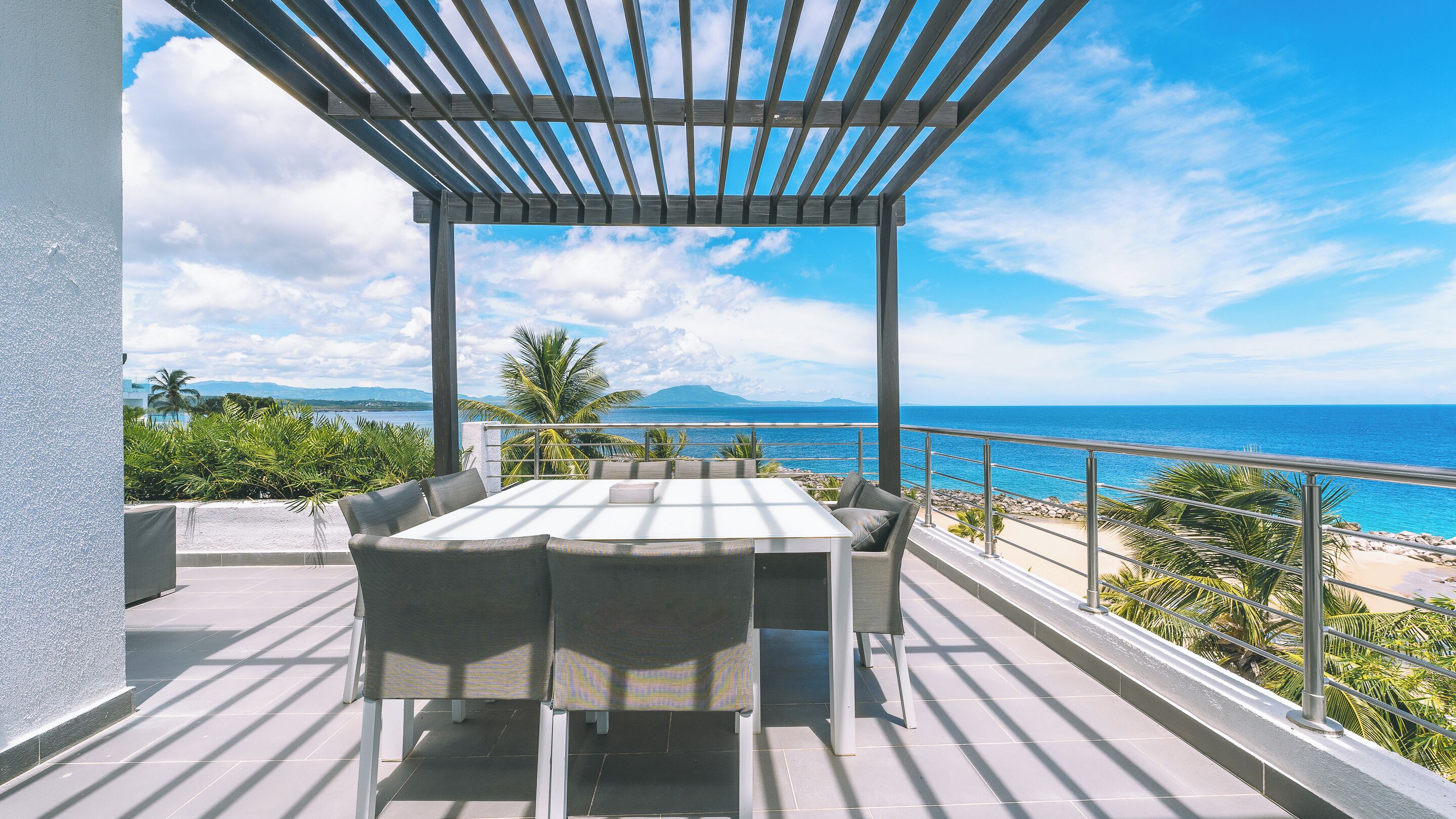 Una terraza con mesa y sillas, con vistas a una playa y al océano.