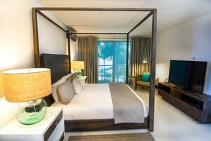 Una habitación de hotel moderna con una cama grande, una televisión, un mueble de televisión y vistas a palmeras a través de la ventana.