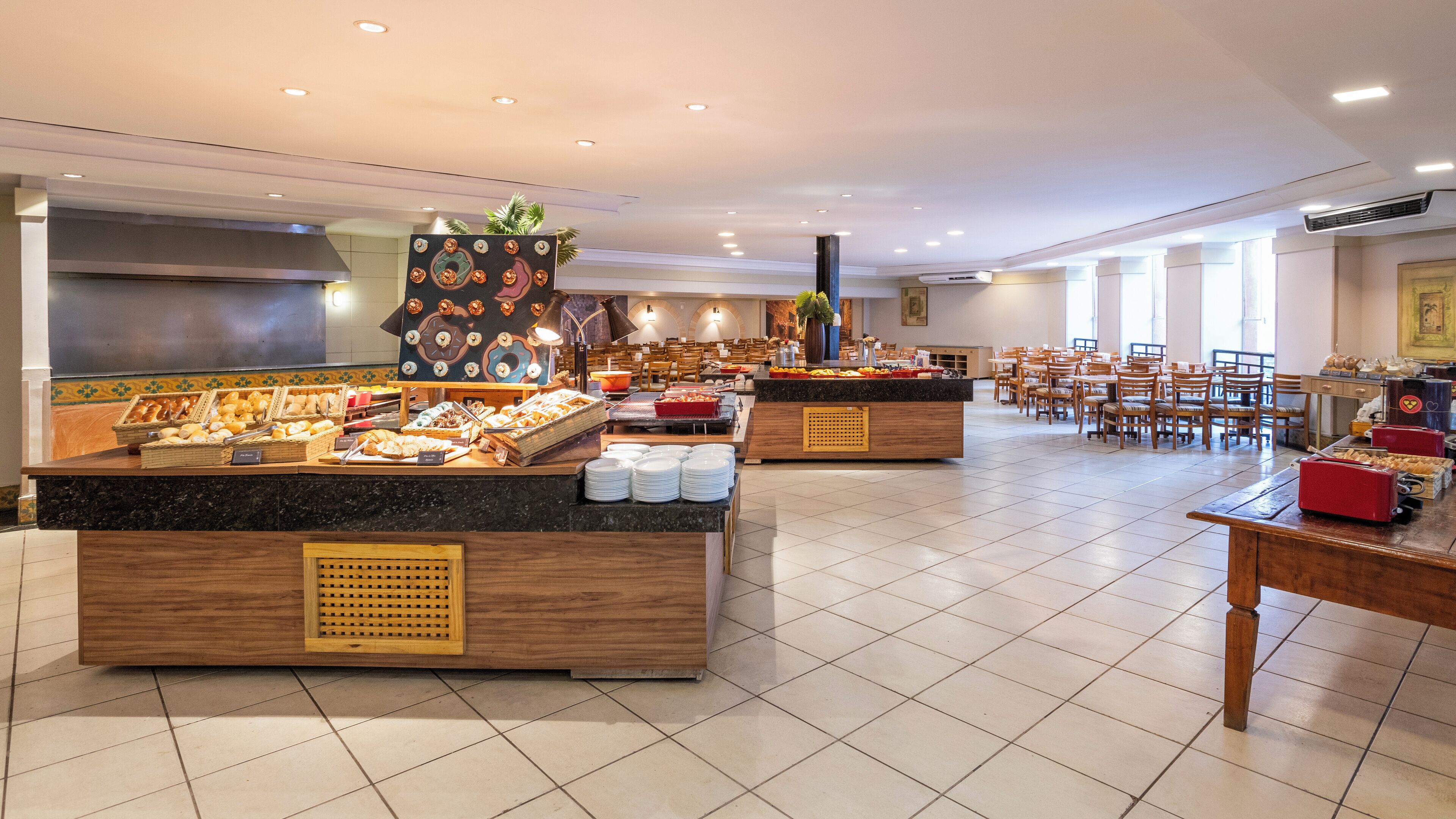 Zona de buffet amb diverses barra de servei, zona de seients amb taules i cadires, i una finestra gran que proporciona llum natural.