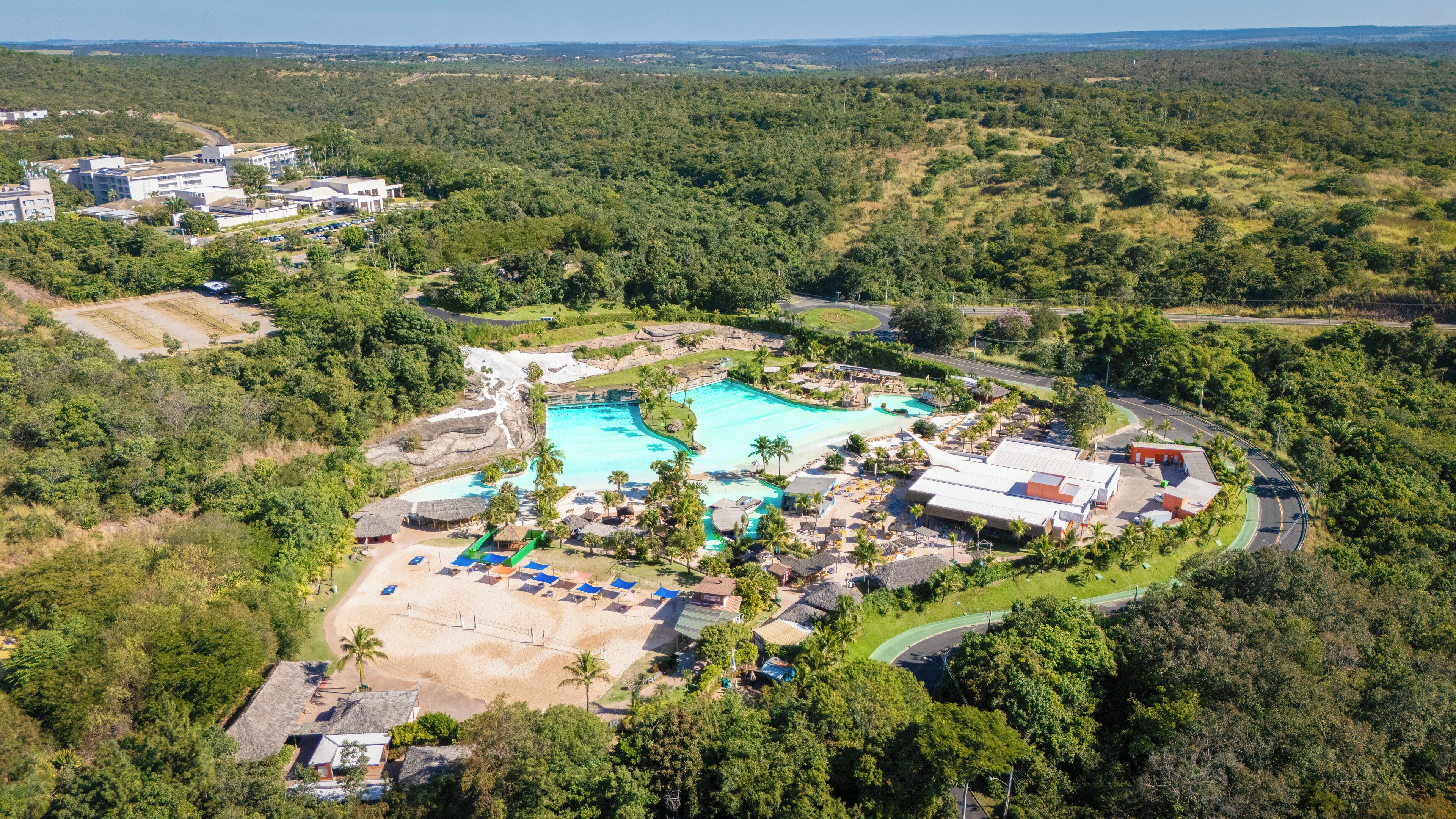 Vista aérea de un complejo turístico con una gran piscina, varias zonas de playa y abundante vegetación alrededor de la propiedad.
