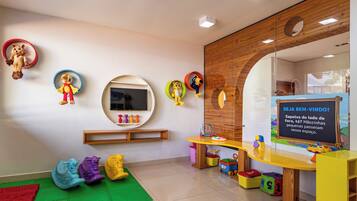 A children's playroom with a large mirror, colorful toys, and a chalkboard with writing.
