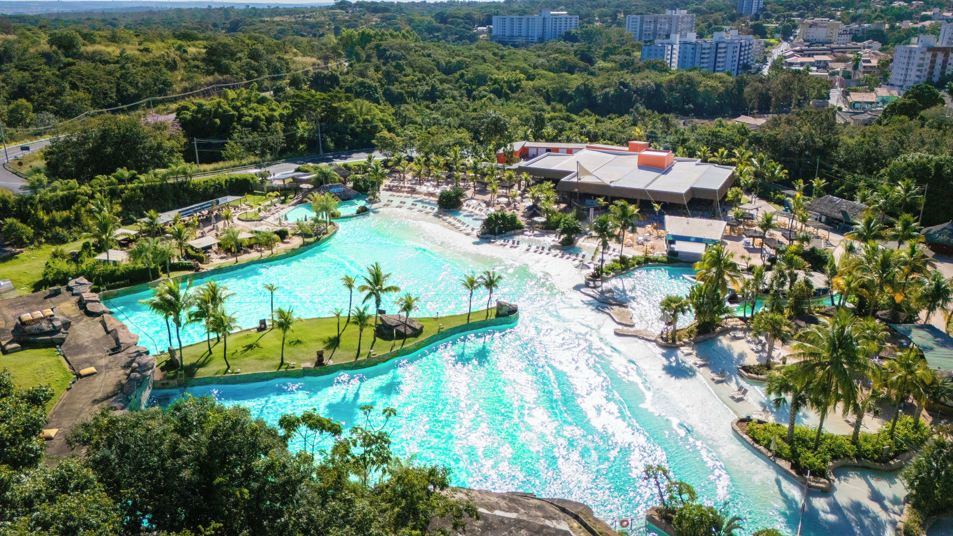 Una vista aerea di un resort con una grande piscina, palme e una spiaggia.