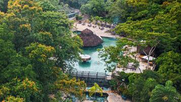 A tropical resort with a pool area surrounded by lush greenery and a bridge over the water.