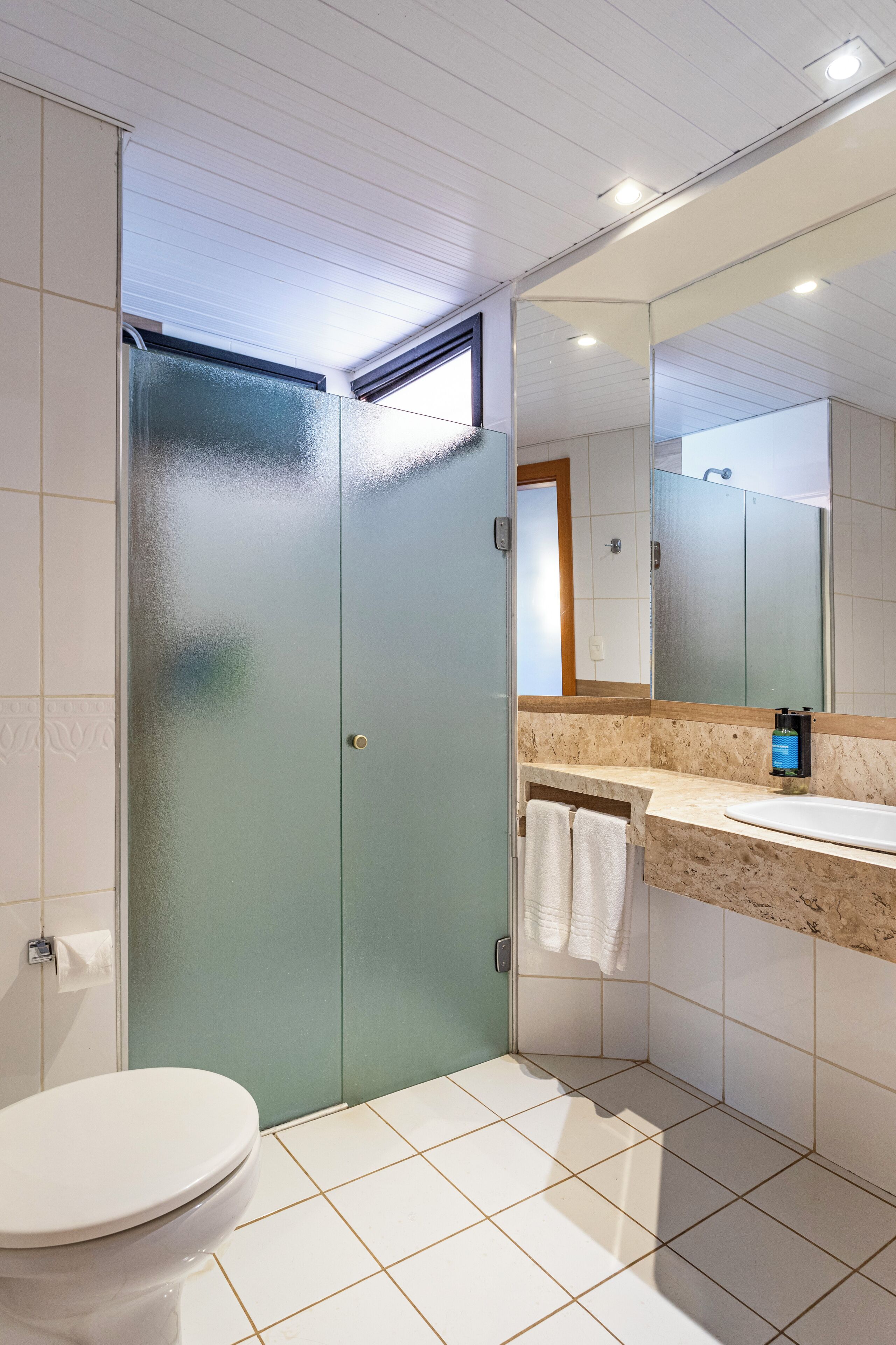 Un bany modern amb un vàter, una dutxa envidriada i un lavabo amb mirall.