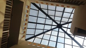Eine hohe Decke mit einem Fenstergitter und einem zentralen Träger.