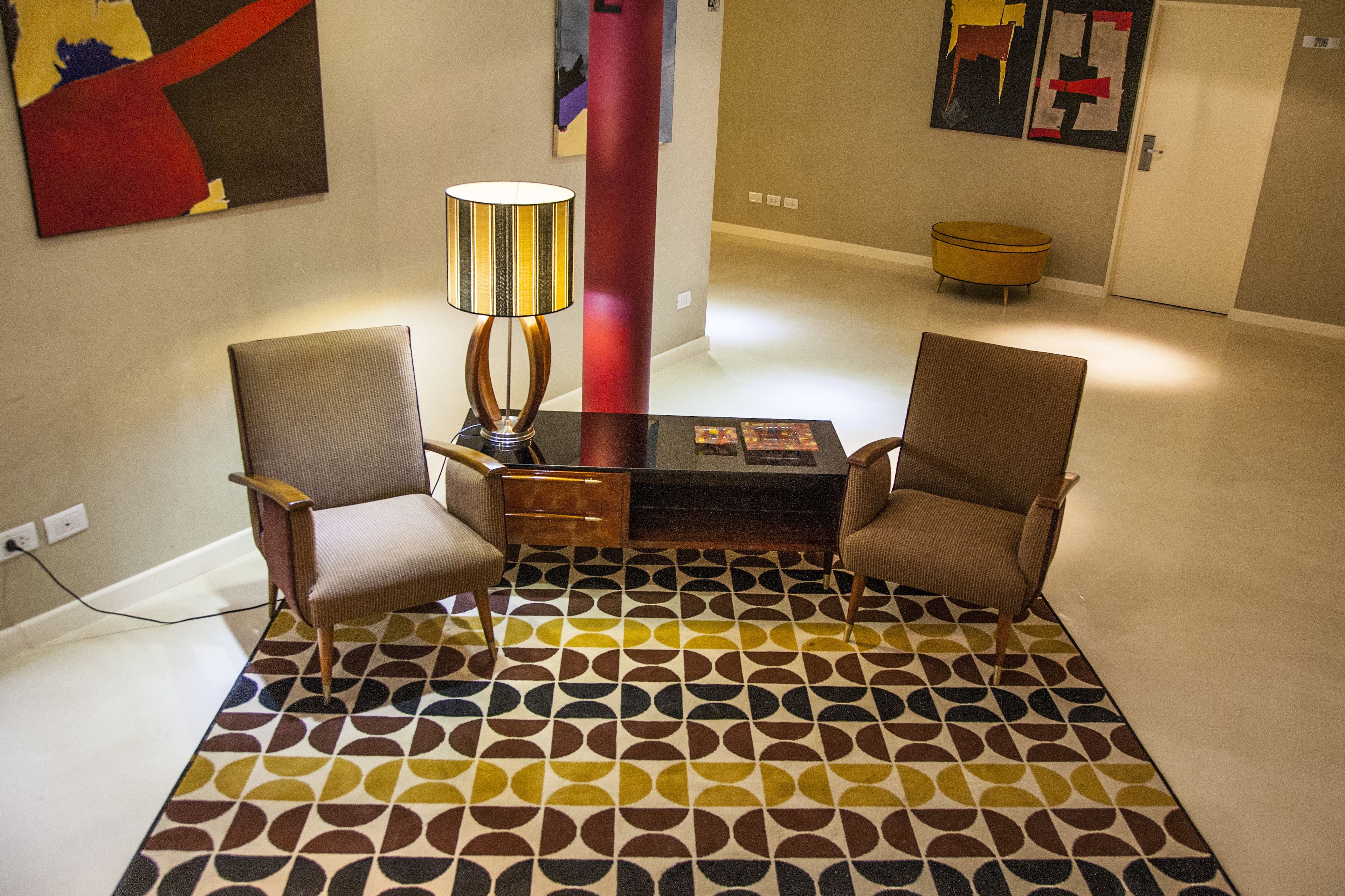 A room with two chairs, a table, and a lamp. There is a patterned rug on the floor.