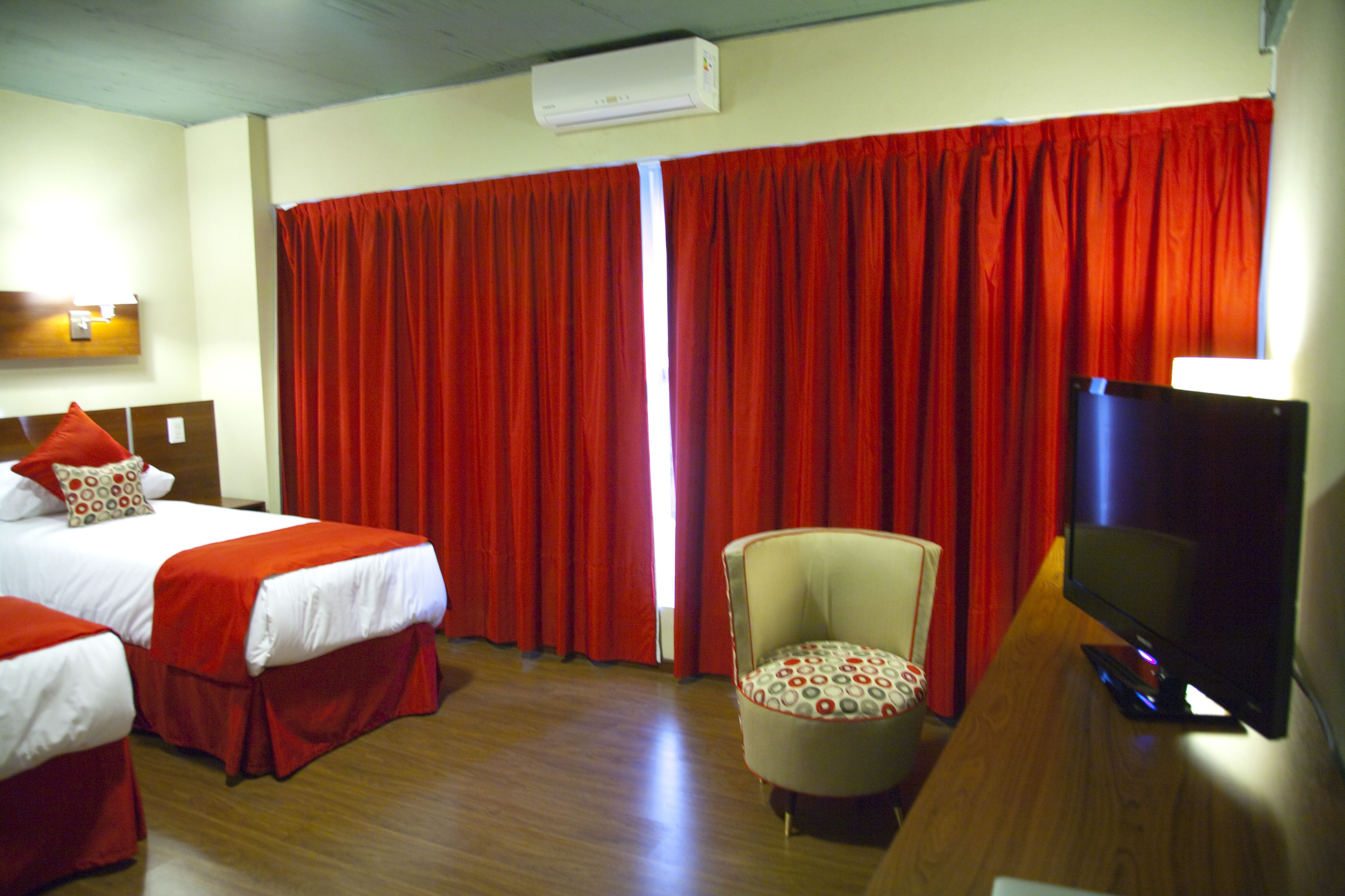 A hotel room with two beds, a TV, and a chair.