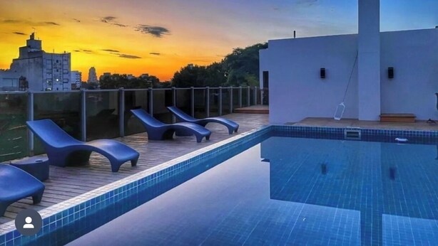 A rooftop pool with lounge chairs and a view of a cityscape at sunset. - First Palermo Viejo Hotel (Buenos Aires)