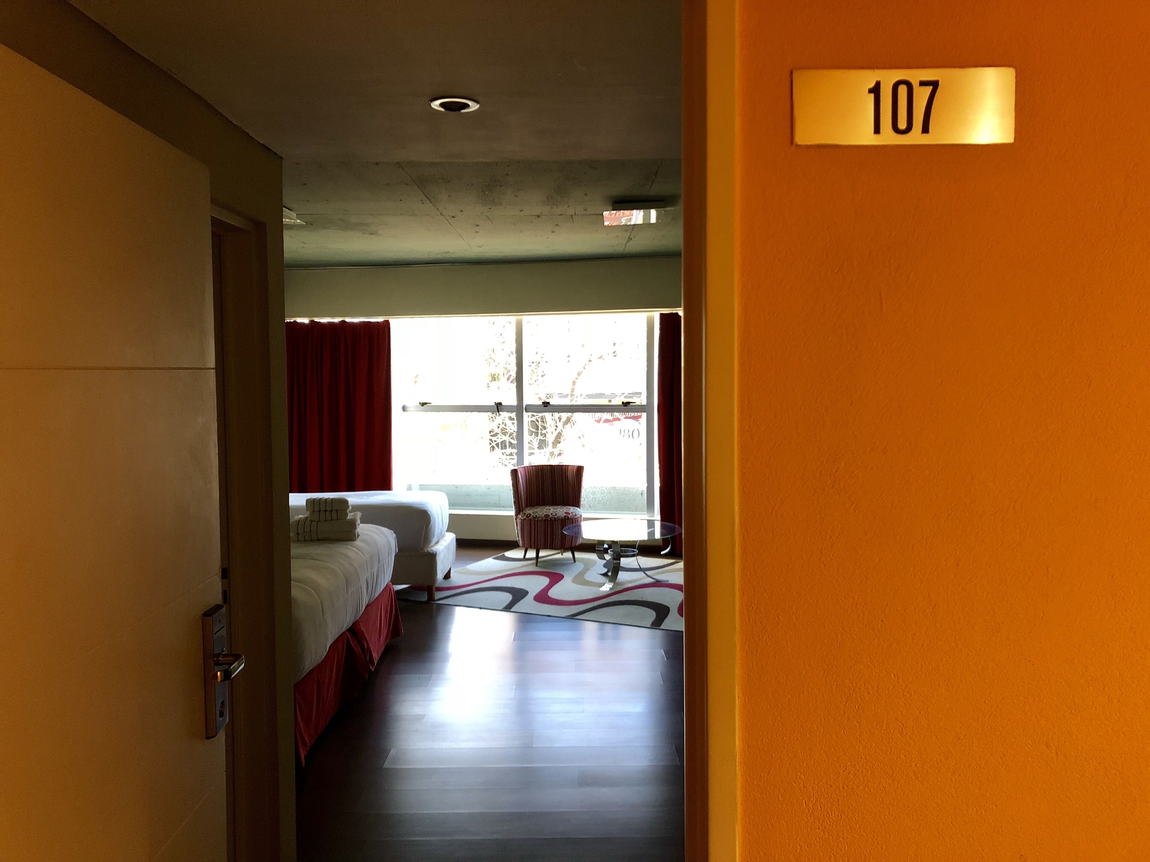 Habitación de hotel con cama, una silla y una ventana.