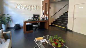 A modern reception area with a desk, computer, and a glass coffee table with a plant. - First Palermo Viejo Hotel (Buenos Aires)