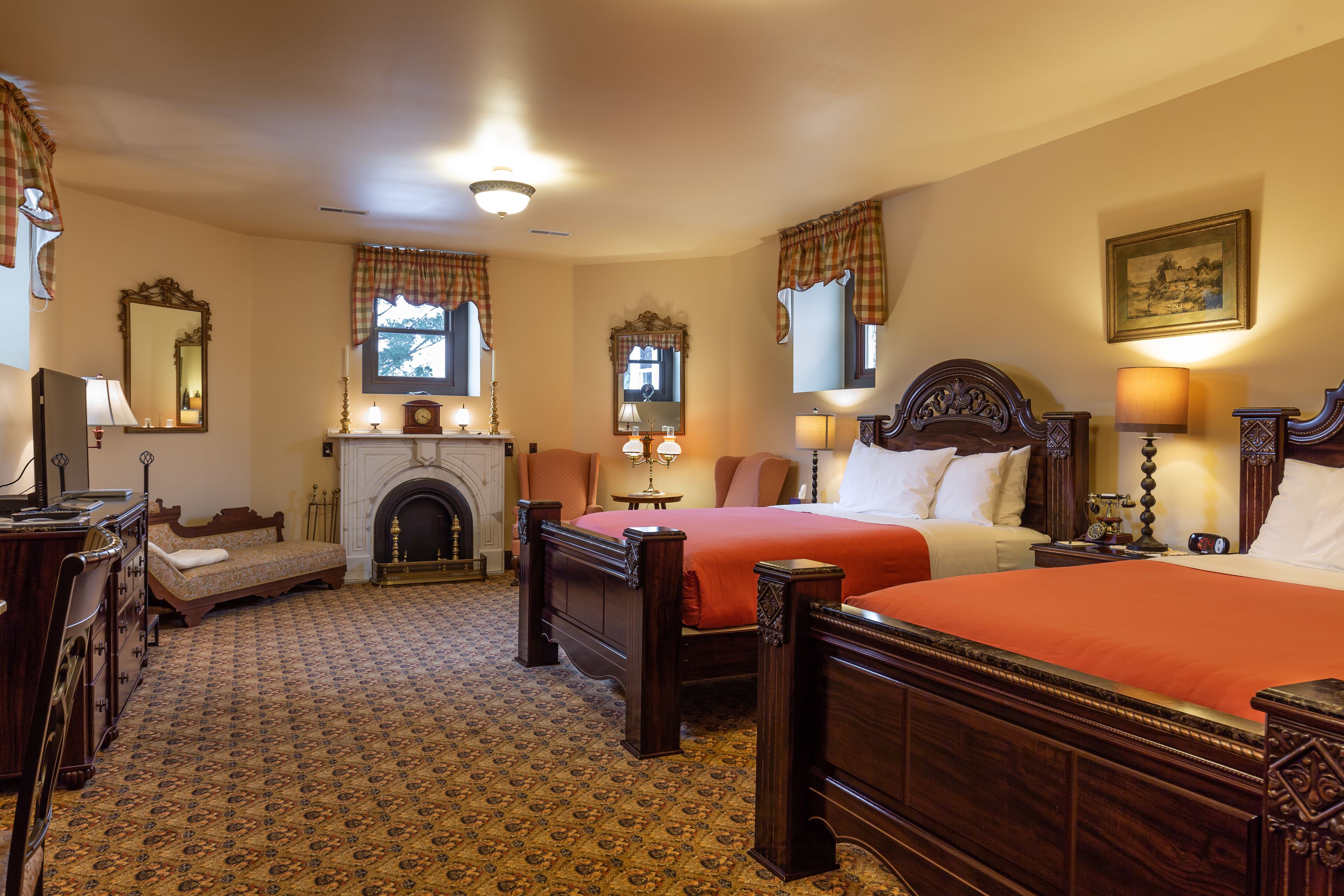 A traditional hotel room with two wooden beds, a fireplace, and classic decor.